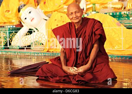 Un monaco si siede di fronte a una statua di Buddha a Shwedagon pagoda in Yangon, Myanmar, 6 febbraio 2013. Foto Stock