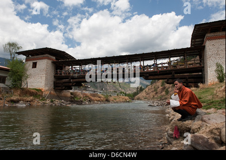 Thimphu, Bhutan, uomo in costume nativo-Goh su un ponte sul fiume mt Foto Stock