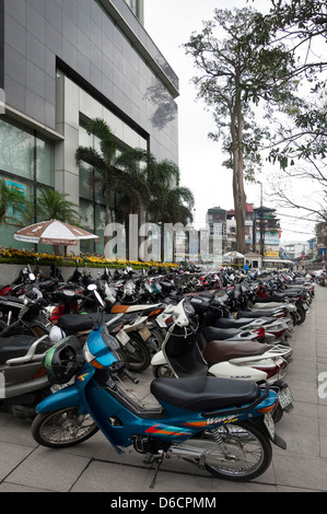 Vista verticale di lotti di ciclomotori, il favorito di una forma di trasporto in Vietnam parcheggiata sul lato della strada. Foto Stock