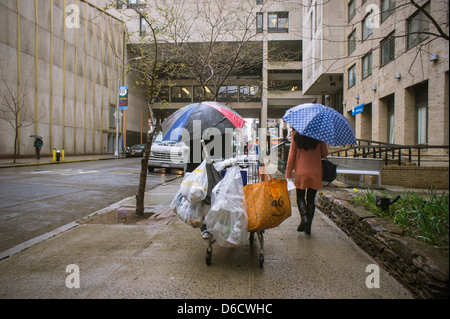 Un deposito di collettore bottiglia passa un pedone nel quartiere di Chelsea di New York Foto Stock