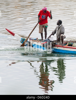 Due uomo senegalesi in una piccola barca sostenendo, uno sterzo con un remo, gli altri il funzionamento di un motore fuoribordo di piccole dimensioni Foto Stock