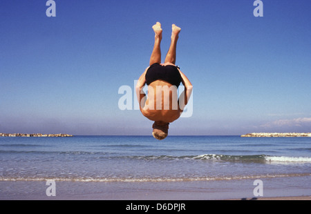 Un giovane turista facendo capriola saltando in Frishman beach in riva al Mar Mediterraneo di Tel Aviv in Israele Foto Stock