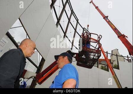 Dpa-esclusivo: l'artista e architetto Yadegar Asisi (L) parla a un membro del team di costruzione sul sito della costruzione del nuovo muro di Berlino panorama al Checkpoint Charlie a Berlino, Germania, 12 settembre 2012. Vienna-nato Asisi utilizzato per vivere nei pressi del muro di Berlino nel quartiere Kreuzberg di Berlino negli anni ottanta. La sua vista panoramica del muro di Berlino combina il suo oggetto Foto Stock