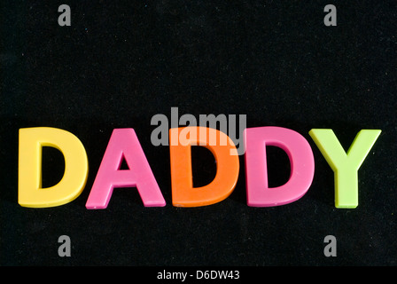 Il Daddy scritto con il giocattolo per bambini è colorato le lettere magnetiche isolate su uno sfondo nero Foto Stock