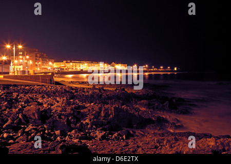 Notte in Porthcawl Galles del Sud, la strada che le luci si accendano il lungomare e la spiaggia rocciosa Foto Stock