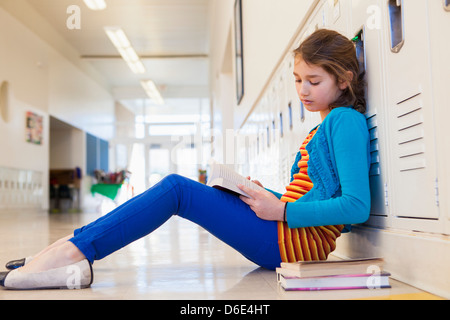 Studente caucasica lettura nel corridoio della scuola Foto Stock