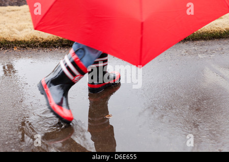 Razza mista boy spruzzi in stivali di gomma Foto Stock