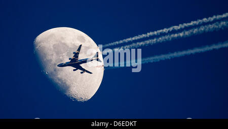 (Dpa-file) - Un file immagine datata 04 aprile 2009 mostra un aereo passato la luna in Sieversdorf, Germania. Il controverso le rotte aeree per il principale aeroporto BER sono presentati al pubblico il 26 gennaio 2012 a Berlino. Foto: Patrick Pleul Foto Stock