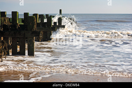 Una vista del legno di un frangiflutti e azione di onda a Bacton-on-Sea, Norfolk, Inghilterra, Regno Unito. Foto Stock