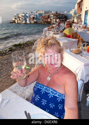 La donna alzando il suo bicchiere sull'isola greca di Mykonos, Grecia Foto Stock