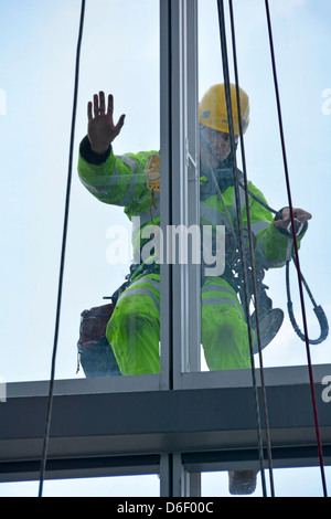 Workman appesi a corde sulla faccia esterna di una torre di Londra edificio a blocco di effettuare lavori di manutenzione alla vetratura Foto Stock