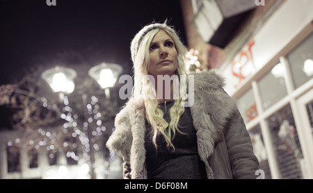 Ritratto di una bella ragazza bionda da solo su una strada di città di notte. Foto Stock