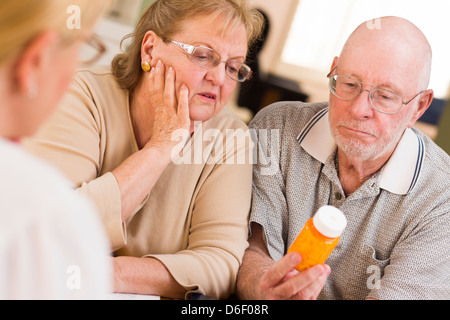 Medico o infermiere spiegando la medicina di prescrizione a un attento Coppia senior. Foto Stock