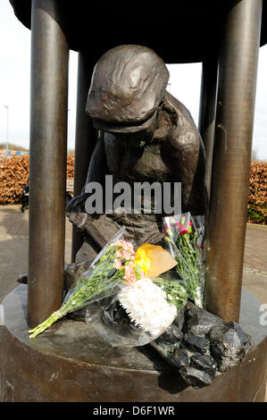 Hucknall,Notts.UK.17 Aprile 2013.local ex minatori lasciare omaggi floreali ai piedi della statua in bronzo che commemora "perso" industria mineraria.Hucknall colliery 1861-1986 era una fossa di lavoro durante lo sciopero degli anni ottanta .ma era ancora chiusa dal governo Thacther.Collier è rappresentato hawing carbone all'interno di ""Il vetro di una lampada di Davy. Credito: Ian Francesco/Alamy Live News Foto Stock