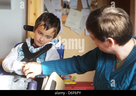 Sterup, Germania, un ragazzo seduto in una sedia a rotelle con un bambini infermiere Foto Stock