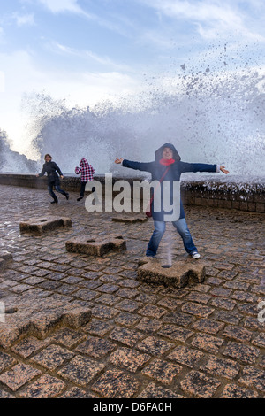 La gente che ottiene imbevuto da onde anomale proveniente da sopra e attraverso la parete del porto di San Sebastián Donostia, Paesi Baschi Foto Stock