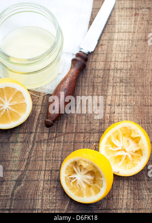 Spremuta di limoni Meyer, succo in un vasetto di vetro, juiced metà di limone su uno spiovente panca di legno Foto Stock