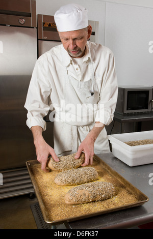Cuoco professionista, preparare il pane fresco in un forno commerciale Foto Stock