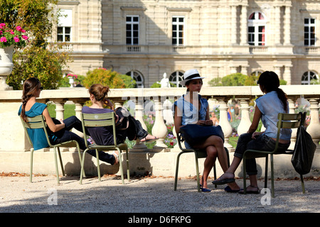 Summer in Paris. Ragazze in chat in seduta famoso giardino di Lussemburgo sedie di fronte al Senat Palace, Parigi, Francia Foto Stock