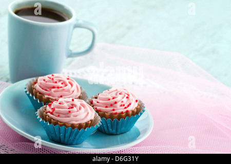 Piastra di colore blu con rosa praline di cioccolato e la tazza di caffè sui colori pastello sfondo, con spazio di copia Foto Stock