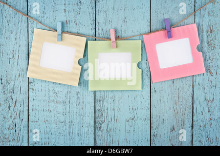 Tre colorate vuote photo frame o carta note appeso con clothespins su legno blu vintage shabby chic di sfondo Foto Stock
