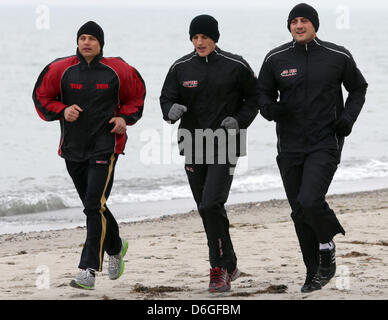 La boxe Pro Francesco Pianeta (R) e Robin Krasniqi (C) lungo la spiaggia con i loro caoch Dirk Dzemski (L) durante un breve training camp di organiser boxe Boxing SES nel Mar Baltico località balneare Dierhagen, Germania, 12 aprile 2013. Foto: Bernd Wuestneck Foto Stock