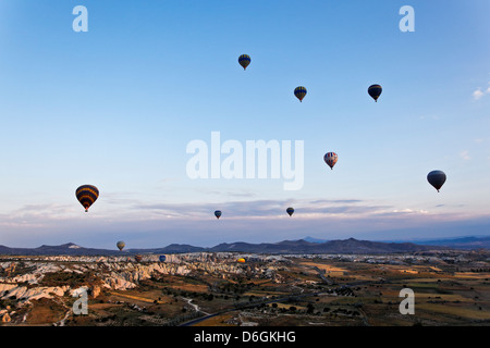 Vista aerea della Cappadocia e pianure di Goreme con le sue montagne e il cielo pieno di variopinte mongolfiere all'alba Foto Stock