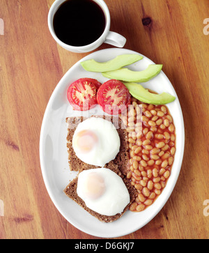 Uova fritte su pane tostato e fagioli al forno per la prima colazione Foto Stock