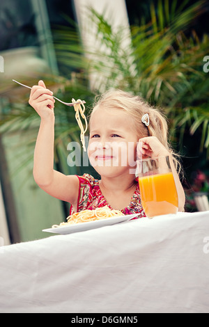 Ragazza Mangiare spaghetti in un giardino Foto Stock