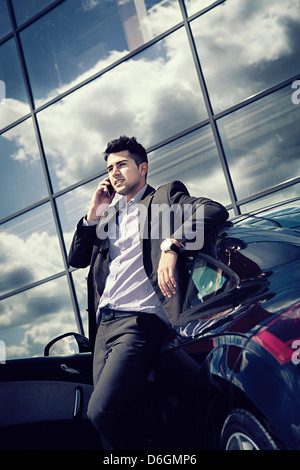 Giovane imprenditore telefonare ad una moderna autovettura Foto Stock