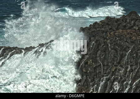 Spruzzi delle onde sulla rocciosa costa di lava Foto Stock