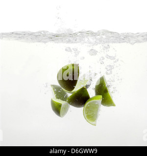 Spicchi di lime schizzi in acqua Foto Stock