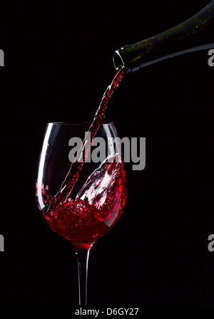 Bottiglia e bicchiere di vino rosso su sfondo nero Foto Stock