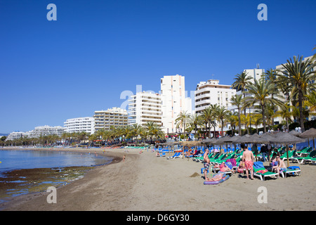 Lettini per prendere il sole e i turisti su una spiaggia sabbiosa presso il famoso resort di Marbella in Spagna, Costa del Sol, Andalusia. Foto Stock