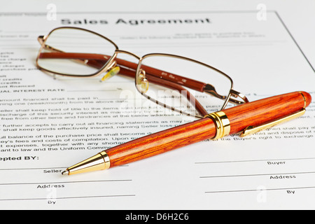 Contratto con gli occhiali e penna in legno pronto per essere firmato. Messa a fuoco selettiva Foto Stock