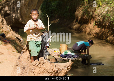 Giovane ragazzo da un flusso mentre sua madre fa il lavaggio - Inn Thein Village 3 Foto Stock