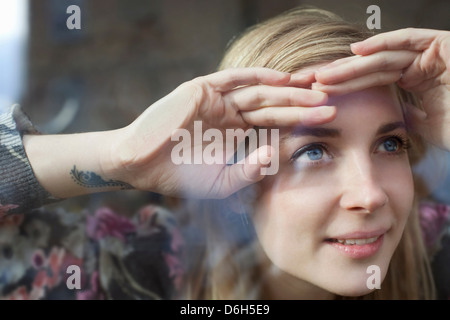 Donna del peering attraverso la finestra Foto Stock
