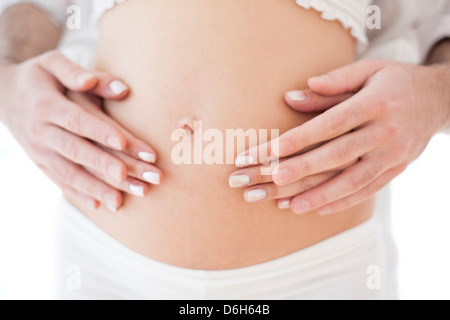 Giovane Azienda della donna incinta, addome Foto Stock