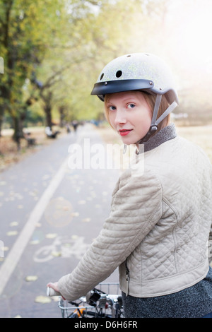 Donna in bicicletta nel parco urbano Foto Stock