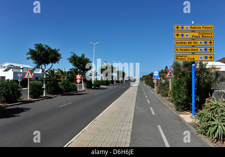 Una vista della segnaletica stradale dirigere traffico da e per gli hotel su una strada rettilinea in Playa Blanca, Lanzarote. Foto Stock