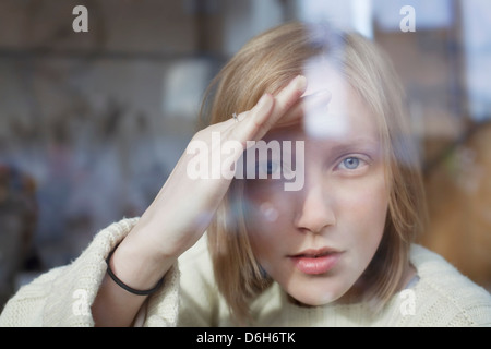 Donna del peering attraverso la finestra Foto Stock