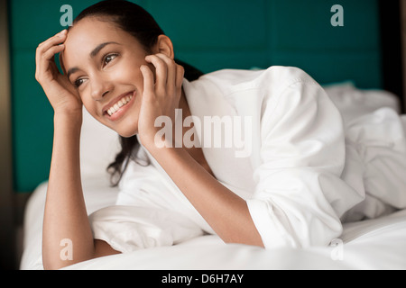 Donna in accappatoio posa sul letto Foto Stock