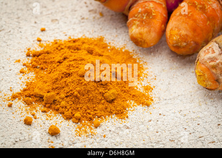 La curcuma in polvere e la radice su un dipinto di bianco di granaio ruvida la superficie di legno Foto Stock