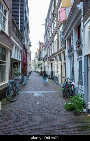 Lone ragazza camminare lungo una tipica strada laterale in Amsterdam. Foto Stock