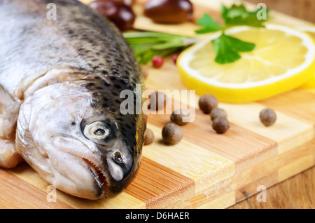 Trota di greggio sul tagliere con limone e spezie Foto Stock