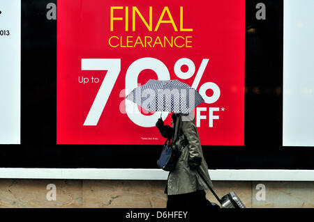 Una donna con un ombrello passeggiate passato una lettura del segno ' liquidazione finale 70% off' Oxford Street, Londra, Regno Unito. Foto Stock