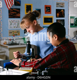 Un ragazzo e una ragazza gli studenti delle scuole medie utilizzando un microscopio nella classe di scienze. Foto Stock