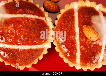 Dolci di mandorla su un piatto rosso con alcune mandorle Foto Stock