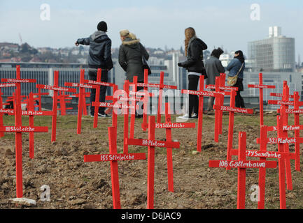 Persone di sostare dietro red croci di legno per gli alberi tagliati nel Schlossgarten di Stoccarda, Germania, 10 marzo 2012. Circa 700 Stuttgart 21 avversari hanno preso parte alla marcia silenziosa contro di tagliare gli alberi nella Schlossgarten per il controverso Stuttgart 21 progetto ferroviario, secondo i rapporti della polizia. Foto: MARIJAN MURAT Foto Stock