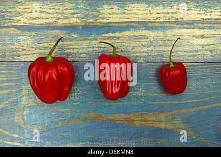 Tre chili peppers su uno sfondo di legno vecchio Foto Stock